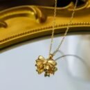 Gold-tone stainless steel bow pendant necklace on fine chain against fabric background