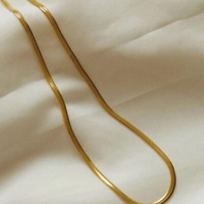 18k gold-plated herringbone chain necklace draped on cream fabric