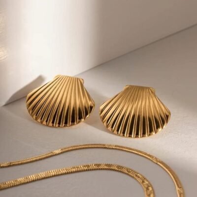 Gold statement earrings shaped like textured seashell on model