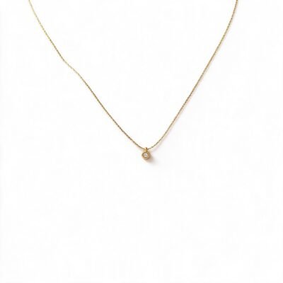 Dainty gold necklace with round crystal pendant worn around the neck
